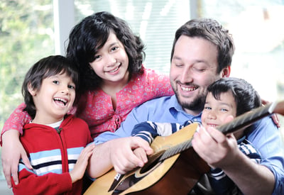 Happy family playing guitar together at home