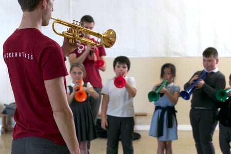 A brass tutor leading a session with young children.