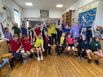 Children from Eversholt Lower School and Emma Eames hold the Yamaha Venova YVS-100 above their heads in a fun pose.