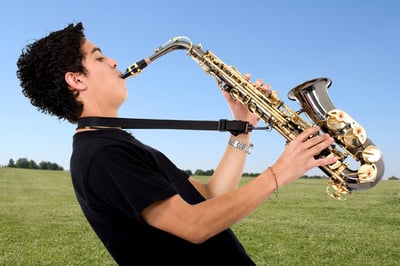 Young man playing music with a sax outdoors