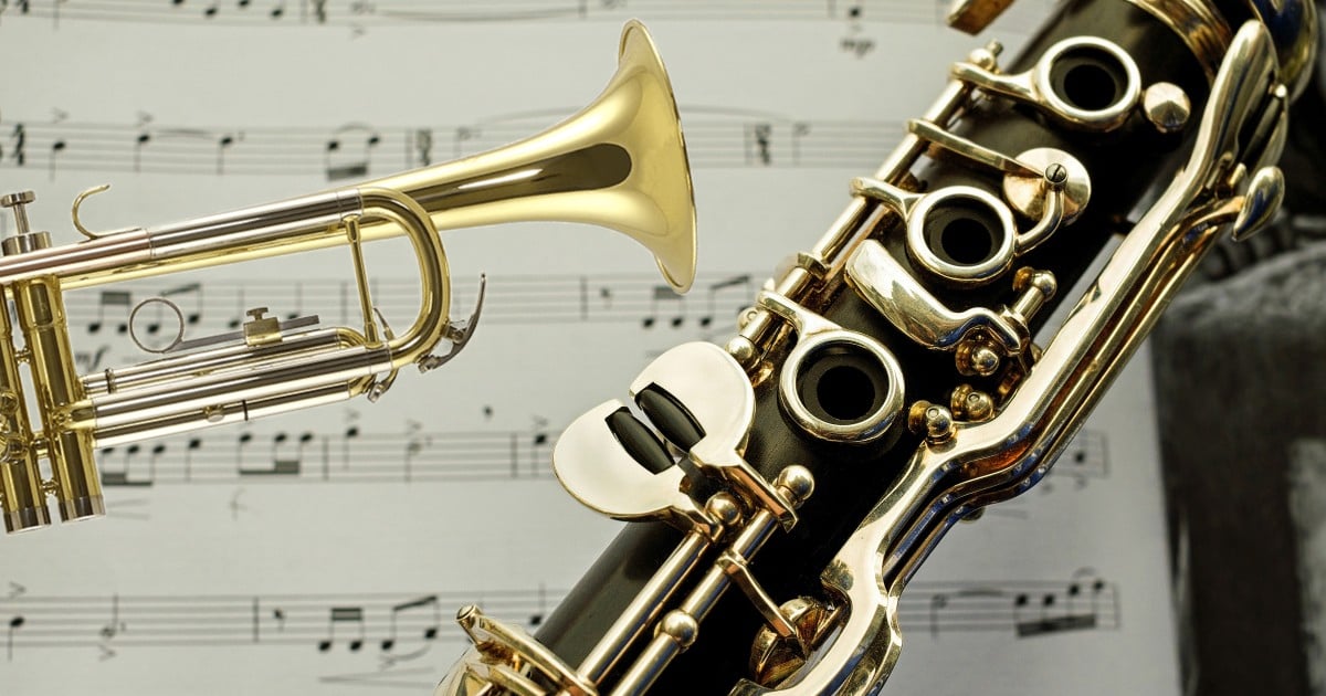 A trumpet and a saxophone pictured in close-up with sheet music.
